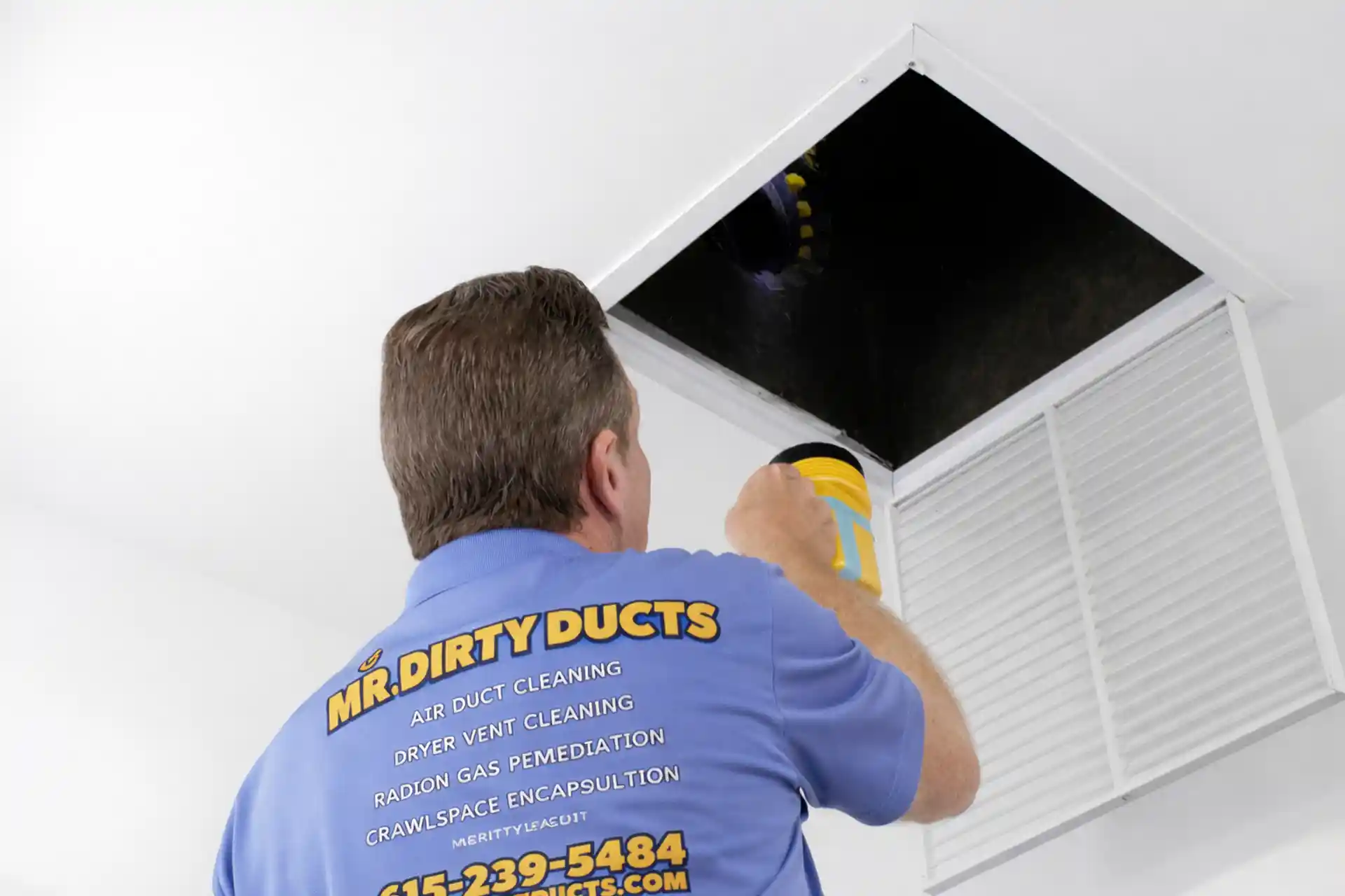 Technician cleaning an air duct with a vacuum hose